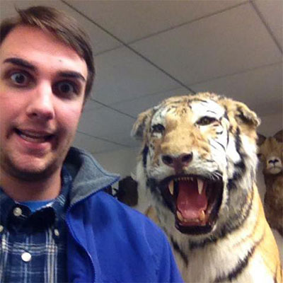 Roy standing in front of a stuffed, giant bengal tiger bearing it's teeth in the USFWS Archive.