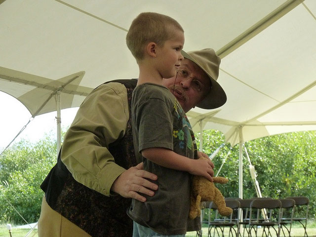 A Teddy Roosevelt impersonator crouches down to speak with a young child.